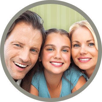 A family of three smiling together in front of a green backdrop.